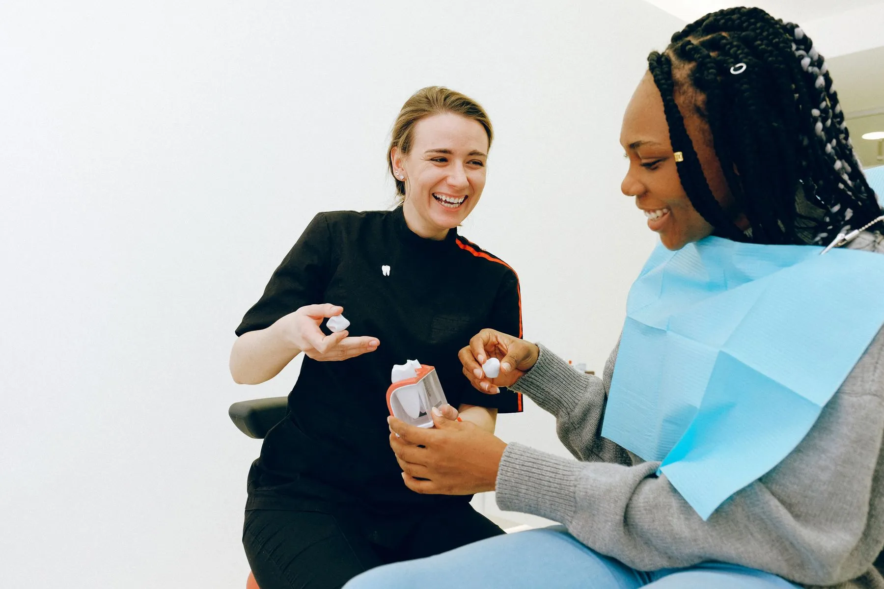 A dentist and patient laughing together during an appointment