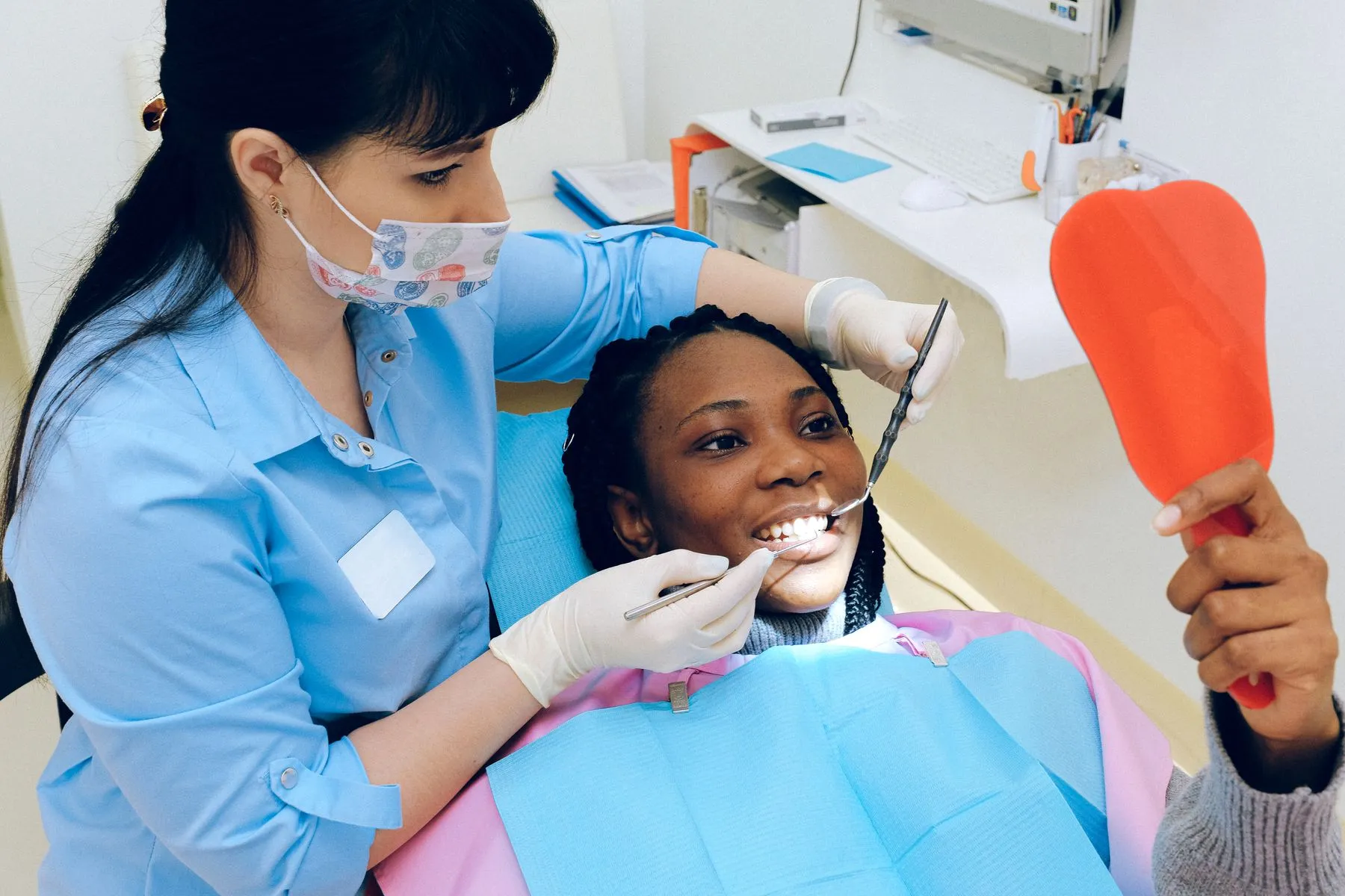 A patient smiling at her reflection in a hand mirror