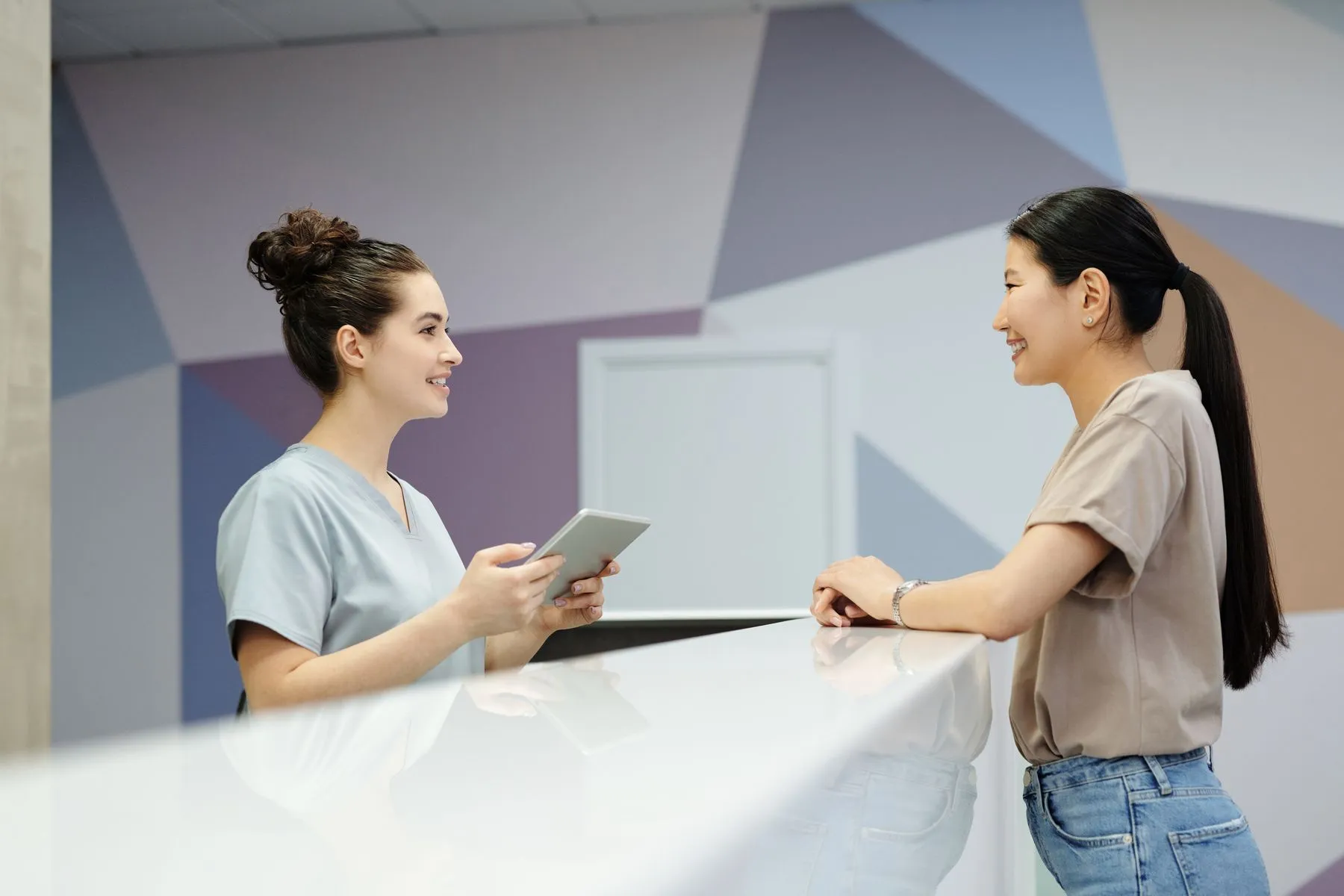 A receptionist with a tablet helping a patient at the front desk